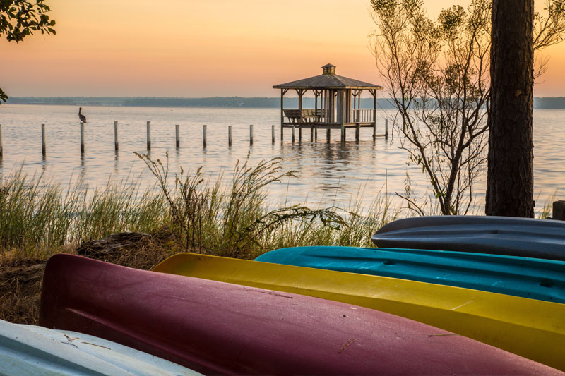 A group of canoes on shore overlooking Mobile Bay