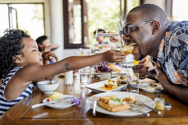 young girl sharing food with dad