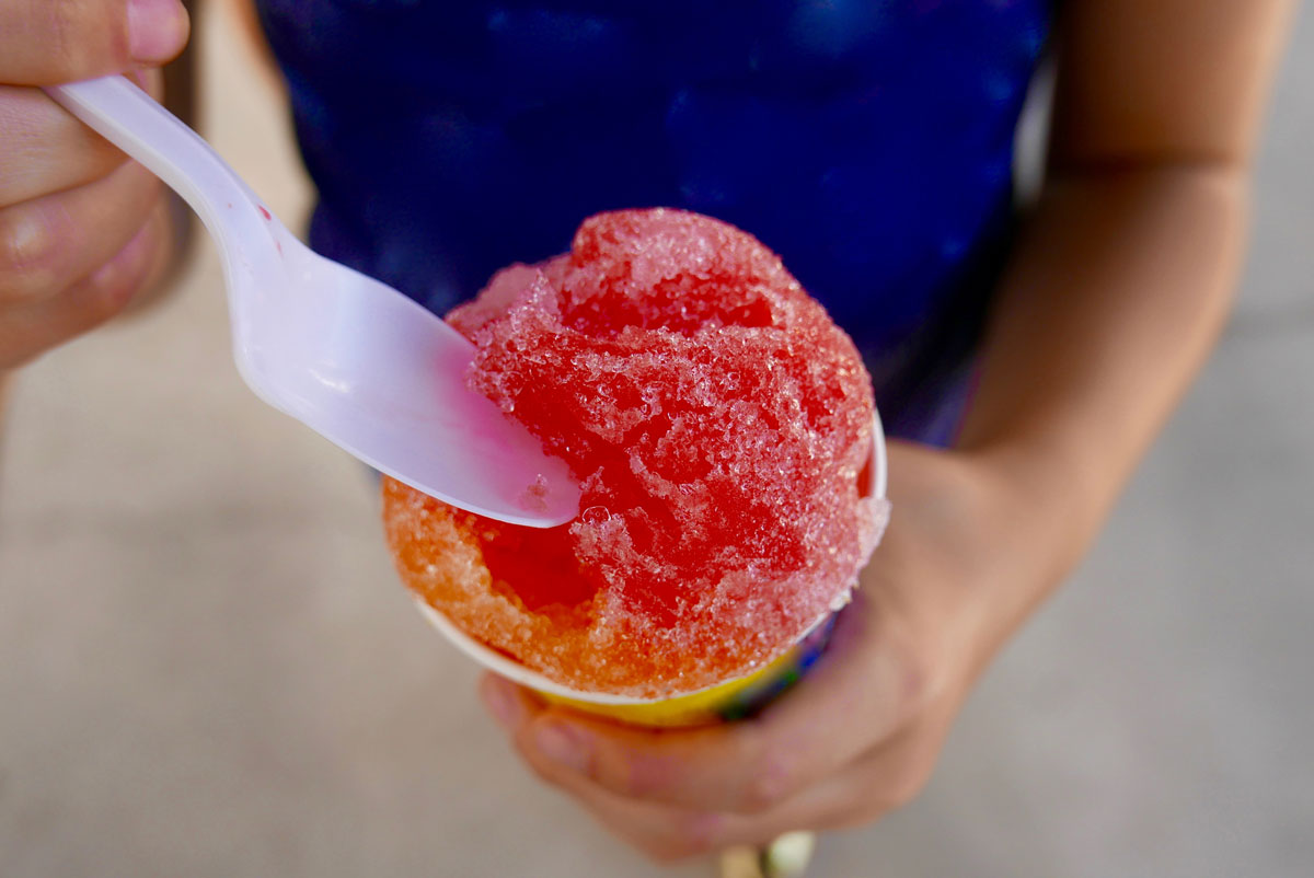 kid holding multi-flavored snow cone